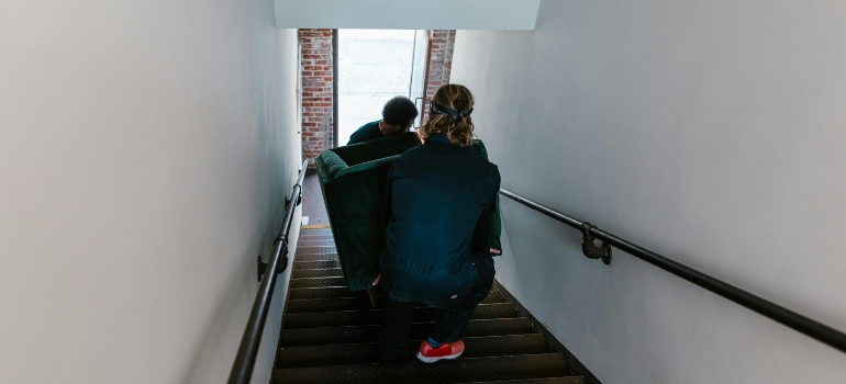 boy and girl holding bed while moving from an apartment to a house