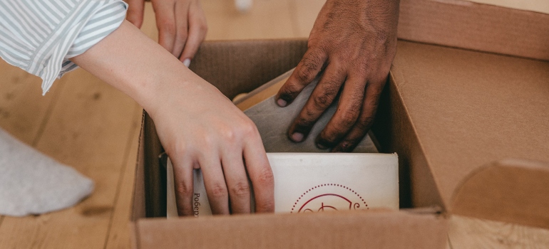 two people packing items in a box